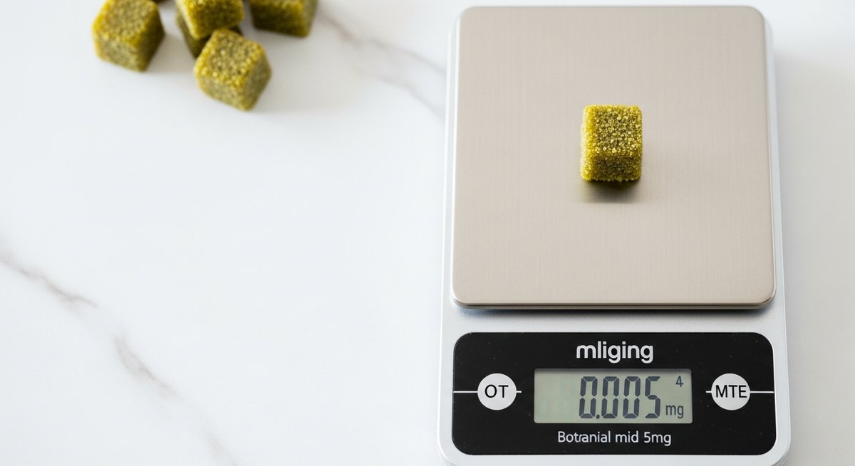 Can Delta-9 Gummies Make Anxiety Worse? What to Know 10 Single gummy on a milligram kitchen scale beside other gummies on a marble countertop, illustrating careful THC dosing.